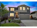 Two-story house with gray and beige siding, a two-car garage, and landscaping, illuminated at night at 4245 S Nepal Cir, Aurora, CO 80013