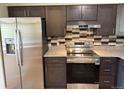 Modern kitchen with stainless steel appliances, granite countertops, and stylish backsplash at 8307 E 14Th Ave, Denver, CO 80220