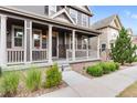 Inviting front porch with classic columns and railing, leading to a well-manicured lawn and entry at 14791 E Poundstone Dr, Aurora, CO 80015