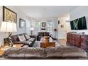 Spacious living room with leather sofas, wood floors, and natural light creating a cozy ambiance at 14791 E Poundstone Dr, Aurora, CO 80015