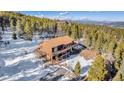Aerial shot of a charming cabin featuring a spacious wooden deck and snow-covered surroundings at 255 Divide View Dr, Golden, CO 80403