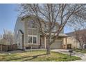 Two-story home with well-maintained lawn and two-car garage, featuring a red front door and stone accents at 9615 Lansing Cir, Commerce City, CO 80022