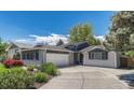 Attractive home showcasing a two-car garage and an inviting driveway with beautiful, mature landscaping at 5071 S Boston St, Greenwood Village, CO 80111