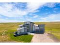 Aerial view of a modern home with a distinctive roof and three-car garage, surrounded by lush greenery at 11680 Imboden Rd, Hudson, CO 80642