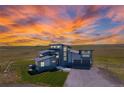 Aerial view of a modern two-story home featuring a unique roofline and three-car garage in a scenic landscape at 11680 Imboden Rd, Hudson, CO 80642