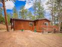 Wood cabin featuring a deck and complemented by flowerpots for added curb appeal at 23778 Inca Rd, Indian Hills, CO 80454
