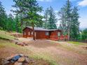 Single story home with a brown exterior, wooden deck, and surrounded by beautiful trees at 23778 Inca Rd, Indian Hills, CO 80454