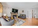 Cozy living room featuring a brick fireplace, hardwood floors, and neutral-colored furniture at 15157 E Nassau Ave, Aurora, CO 80014