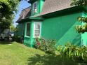 This is a charming green two-story home with a green grass lawn, and mature roses at 4047 Lowell Blvd, Denver, CO 80211