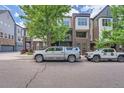 Modern townhome with brick and siding, featuring a balcony and tree-lined street at 467 S Reed Ct, Lakewood, CO 80226