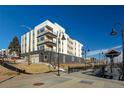 Modern apartment building exterior with multiple balconies, street lights and nearby train station at 1208 N Quitman St # 402, Denver, CO 80204