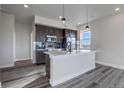 Open concept kitchen with quartz countertops, stainless steel appliances, and gray wood flooring at 1208 N Quitman St # 402, Denver, CO 80204