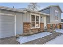 Home's exterior features gray siding, brick details, and a two-car garage at 16046 E Harvard Ave, Aurora, CO 80013