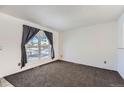 Bright living room with large window, neutral walls, and dark gray carpeting at 16046 E Harvard Ave, Aurora, CO 80013