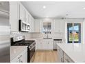 Bright kitchen featuring stainless steel appliances, white cabinets, and ample counter space at 9175 Uravan Ct, Commerce City, CO 80022