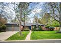 Charming brick home featuring a manicured front yard, mature trees, and a three-car garage at 4011 S Ivy Ln, Cherry Hills Village, CO 80111
