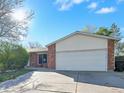 This one-story home features brick accents, a two-car garage, a well-manicured lawn, and mature landscaping at 10878 Grange Creek Dr, Thornton, CO 80233