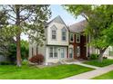 Charming two-story townhome with light-colored siding, gray trim, mature trees and a lush green lawn at 9946 W Cornell Pl, Lakewood, CO 80227