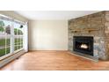 Cozy living room featuring a stone fireplace, hardwood floors, and large windows for ample natural light at 9946 W Cornell Pl, Lakewood, CO 80227