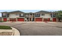 Street view of gray townhouses featuring red garage doors and manicured landscaping at 9300 E Florida Ave # 906, Denver, CO 80247