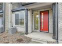 Charming front entrance with a vibrant red door, contrasted by the light brick and dark accents at 1755 Peak Loop, Broomfield, CO 80023