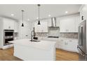 A kitchen with white cabinets, stainless steel appliances, a kitchen island, and hardwood floors at 42966 Colonial Trl, Elizabeth, CO 80107