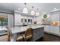 Bright kitchen with white cabinets, gray island, stainless appliances, and modern pendant lighting at 5955 Blue Sage Way, Littleton, CO 80123
