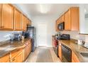 Efficient galley kitchen with granite counters, wood cabinets, and modern appliances for cooking at 9335 Amison Cir # 203, Parker, CO 80134