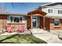 Inviting front porch with covered entry, brick facade, and cozy seating area with bright chairs at 13915 W 73Rd Ave, Arvada, CO 80005