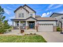 Charming two-story home with a covered front porch, featuring stone accents and a two-car garage at 703 Tiger Lily Way, Highlands Ranch, CO 80126