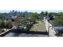 An aerial shot shows a vacant lot surrounded by mature trees, with the city skyline visible in the background at 1735 W 37Th, Denver, CO 80211