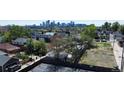 An aerial view captures a vacant lot surrounded by mature trees and neighboring homes, with the city skyline in view at 1735 W 37Th, Denver, CO 80211