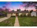 Charming single-story home at twilight, featuring a well-manicured lawn and a welcoming red front door at 4906 E Bates Ave, Denver, CO 80222