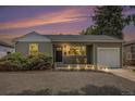 Charming single-story home with warm exterior lighting and a meticulously landscaped front yard at dusk at 1920 Elmira St, Aurora, CO 80010