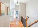 Inviting hallway with hardwood floors, decorative railing, and views to living spaces at 577 Tristan Pl, Berthoud, CO 80513