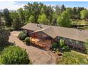 Aerial view of a brick house surrounded by lush greenery and a wooden deck at 5460 S Olive St, Greenwood Village, CO 80111