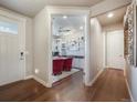 Hallway view showcasing hardwood floors and a glimpse into the bright and functional office space with built-ins at 15776 Native Willow Dr, Monument, CO 80132