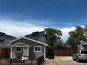 Cozy single-story home with gray siding, complemented by lush greenery and a 'For Sale' sign at 1533 E Harlan, Lakewood, CO 80214