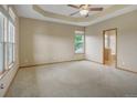 Spacious main bedroom with tray ceiling, plush carpet, and abundant natural light from multiple windows at 16231 Rayburn St, Hudson, CO 80642