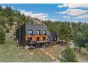 Daytime exterior of modern mountain home, featuring a large deck and surrounding landscape at 6640 Kilimanjaro Dr, Evergreen, CO 80439