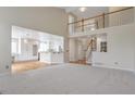 Open-concept living room boasts a soaring ceiling, staircase with wooden railing, and an adjacent kitchen area at 20271 E Lake Ave, Centennial, CO 80016