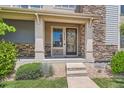 Inviting front porch with stone accents and a decorative front door at 15437 W 95Th Ave, Arvada, CO 80007