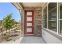 Close up of a modern red front door with glass panels and stone detailing at 21044 E 63Rd Dr, Aurora, CO 80019