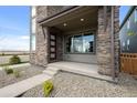 Inviting front porch featuring stone accents, a modern door, and a well-maintained walkway at 21044 E 63Rd Dr, Aurora, CO 80019