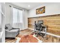 Bright home office featuring a wood accent wall, hardwood floors, and a comfortable chair at 2594 Scoter Ln, Castle Rock, CO 80104