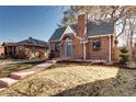 Quaint brick home featuring a chimney and gabled roof, complemented by a well-manicured lawn at 1378 Forest St, Denver, CO 80220