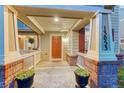 Close-up of a welcoming covered front porch with brick accents and a vibrant orange front door at 13053 Umatilla Ct, Denver, CO 80234