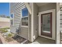 Exterior view of a house with gray siding and a red front door and landscaped yard at 4327 E 98Th Pl, Thornton, CO 80229