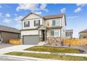 Two-story home with stone accents, gray siding, a two car garage, and a well-maintained lawn at 837 Ledge St, Lochbuie, CO 80603