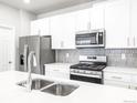 Modern kitchen featuring white cabinets, stainless steel appliances, and a spacious quartz countertop island at 22495 E 7Th Pl, Aurora, CO 80018